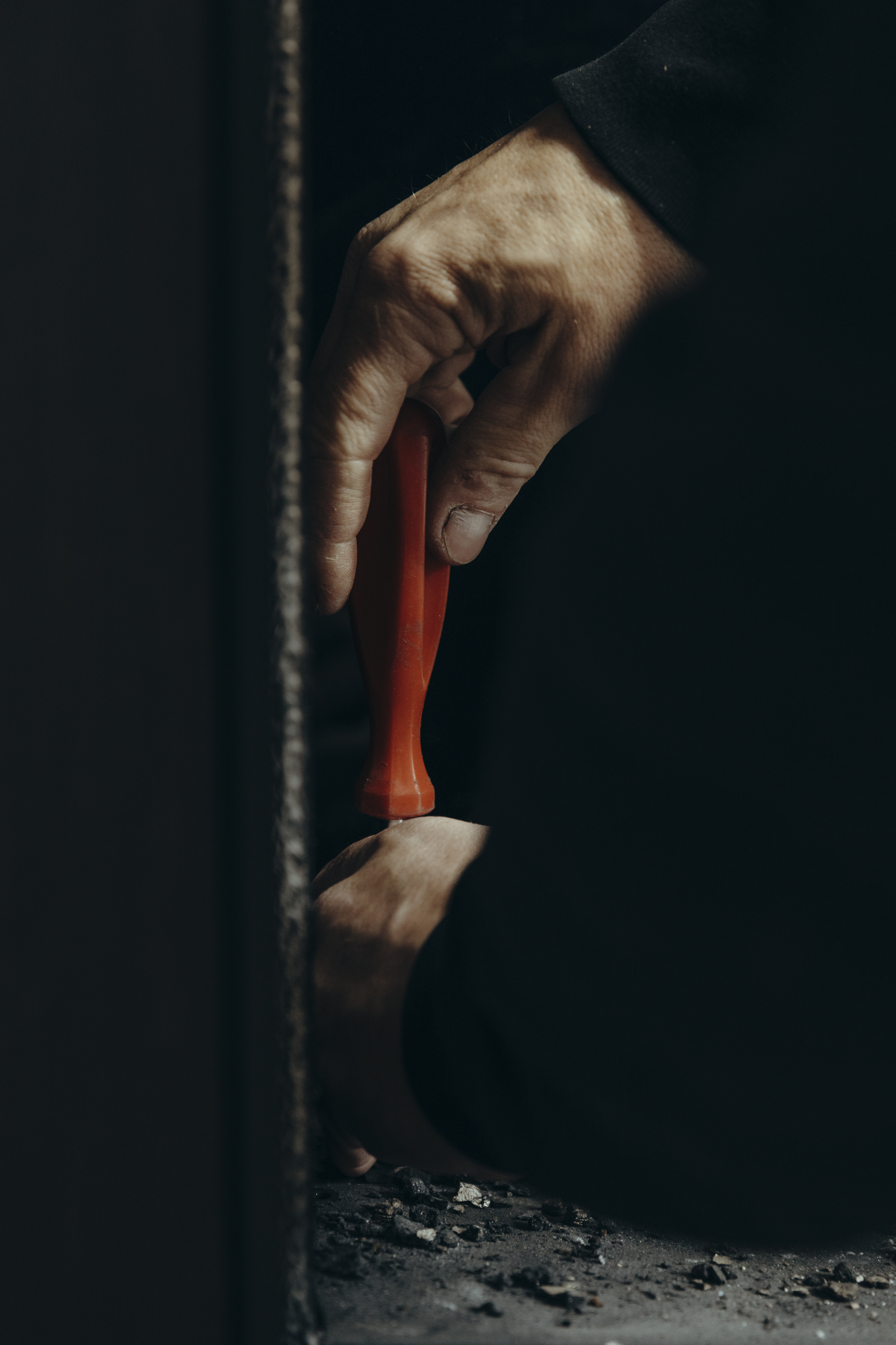 Close-up van een monteur die met een schroevendraaier werkt aan het onderhoud van een haard. Regelmatig professioneel onderhoud is essentieel voor de veiligheid en optimale prestaties van de haard.