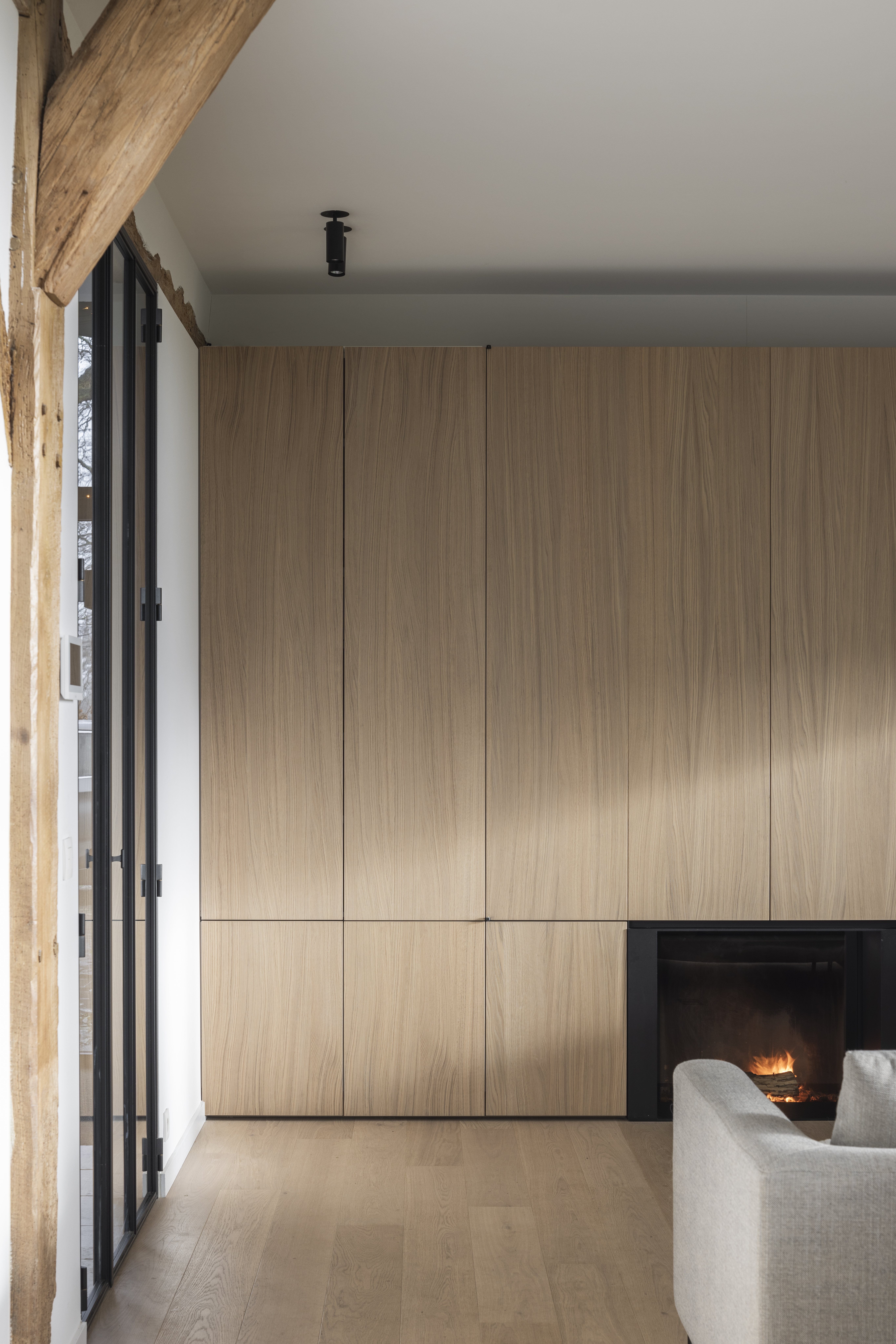 Landelijke woonkamer met houten wanden en een ingebouwde haard, die warmte en rust uitstraalt in een natuurlijke setting.