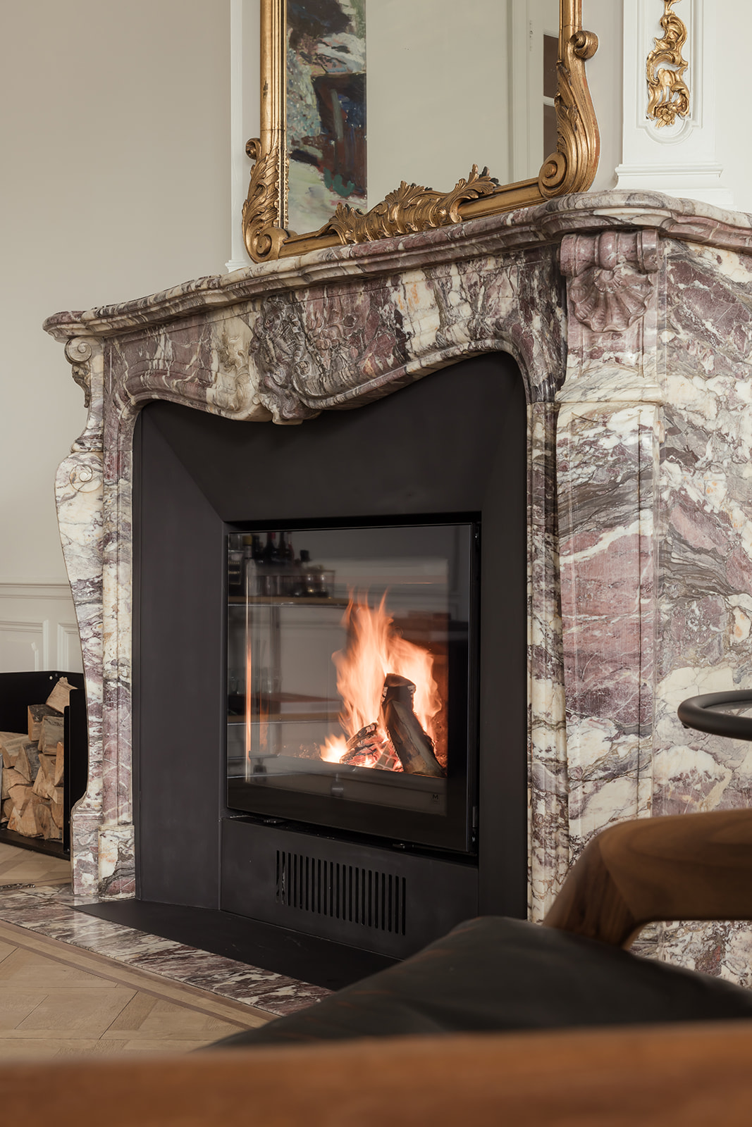 Elegante marmeren houthaard in een klassieke woonkamer, brandend vuur zorgt voor warmte en sfeer.
