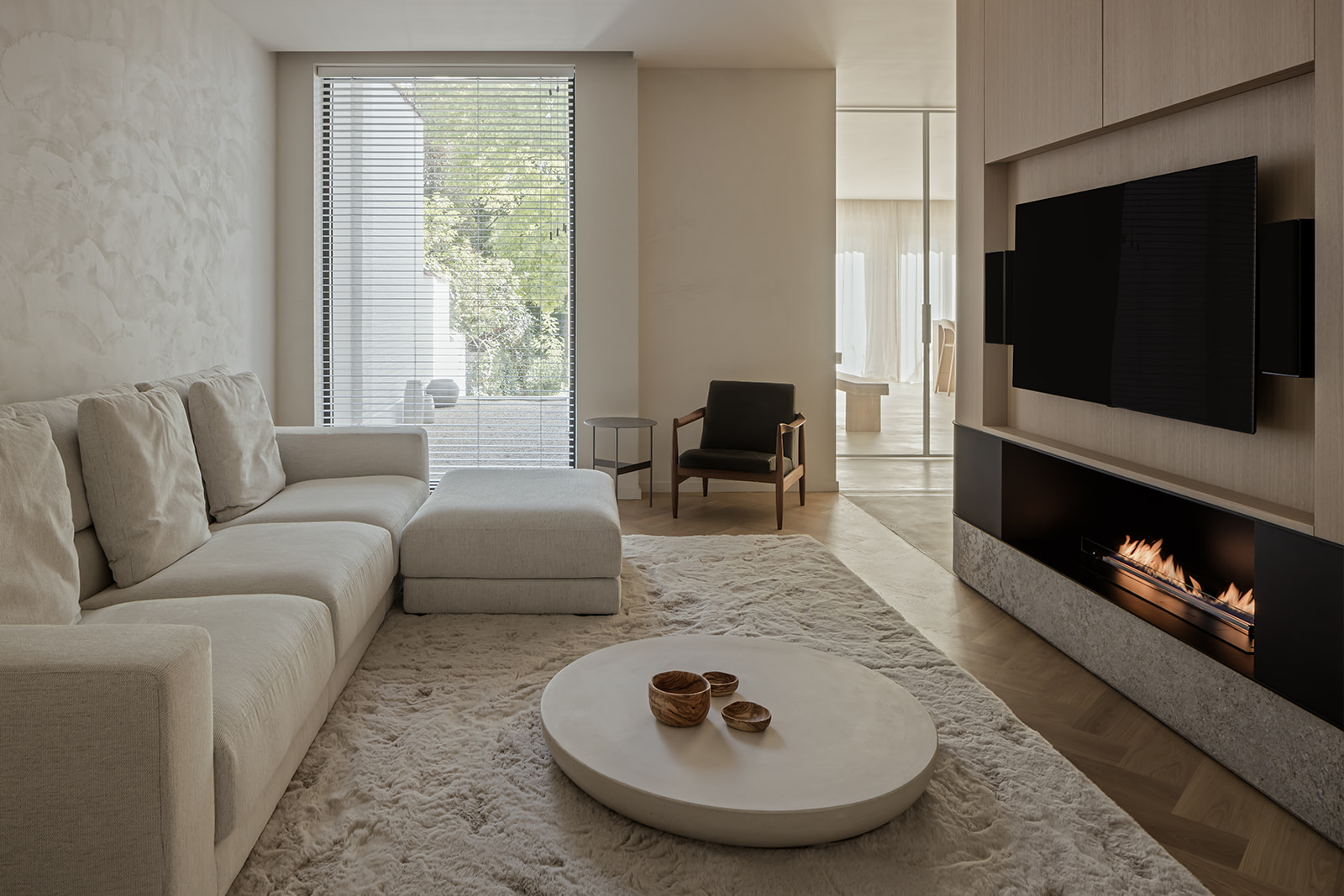 Gezellige woonkamer met een strak tv-meubel en ingebouwde haard, perfect geïntegreerd voor een moderne en warme sfeer.